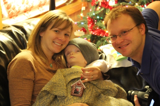 Megan and David Mathis holding Henryk with his Christmas gift ornament (Baby's First Christmas)